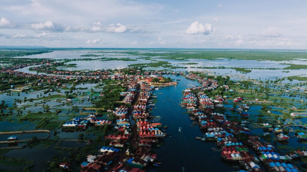 Aerial view of Kampong Khleang floating village on Tonle Sap Lake, Cambodia, showcasing colorful stilt houses and waterways.
